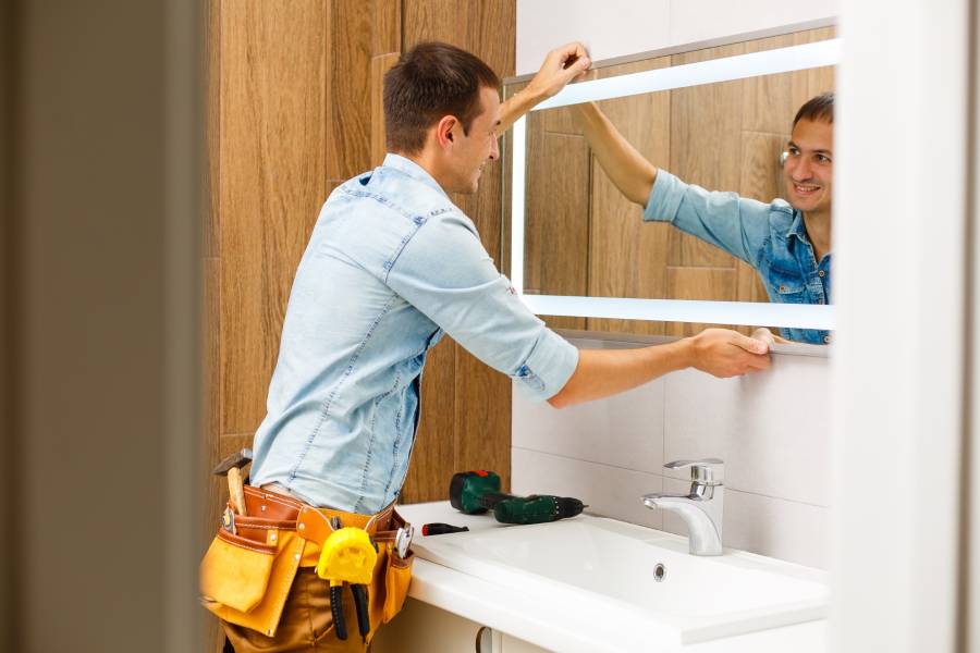 Mann montiert Spiegel in einem Badezimmer